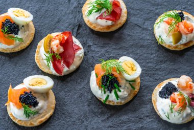 Somon, tedavi bresaola, kerevit, havyar, bıldırcın yumurtası ve ekşi krema - gurme parti gıda - üstten görünüm ile kokteyl blinis yelpazesi