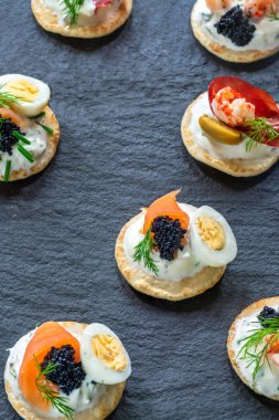 Somon, tedavi bresaola, kerevit, havyar, bıldırcın yumurtası ve ekşi krema - gurme parti gıda - üstten görünüm ile kokteyl blinis yelpazesi