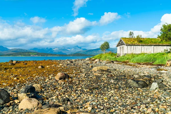 石のビーチと島 Tromsoya ノルウェーのフィヨルドに古い木造の小屋 — ストック写真