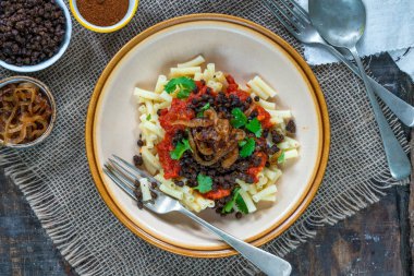 Kushari - Mısır vejetaryen tabağı ile mercimek, kızarmış soğan - üstten görünüm ile tepesinde makarna ve domates sosu baharatlı
