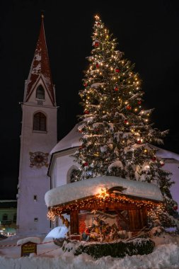 Seefeld, Avusturya - 07 Ocak 2019: Noel ağacı dışında gece görünümünü St. Oswald Parish Kilisesi Seefeld Tyrol Avusturya durumunda bir dev kar ile kaplı