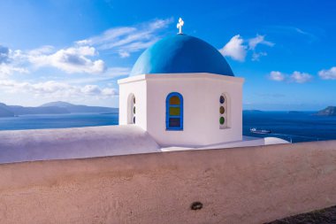 Kaldera ve Ege Denizi manzaralı mavi gökyüzüne karşı Oia geleneksel beyaz badanalı kilisenin mavi kubbe, Santorini, Yunanistan