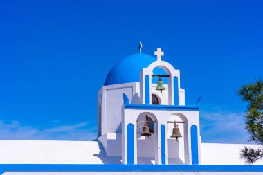 Oia yakınlarındaki tepede beyaz badanalı bir Yunan kilisesinin mavi kubbe ve çan kulesi, Santorini, Yunanistan