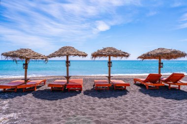 Perissa, Santorini, Yunanistan'daki siyah kumlu plajda boş şezlong ve şemsiyeler