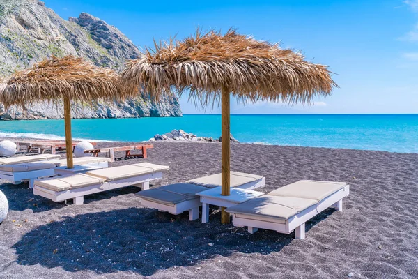 Perissa, Santorini, Yunanistan'daki siyah kumlu plajda boş şezlong ve şemsiyeler
