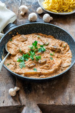 Bir tavada düğme mantar ve maydanoz ile kremsi cajun sos domuz pirzolası