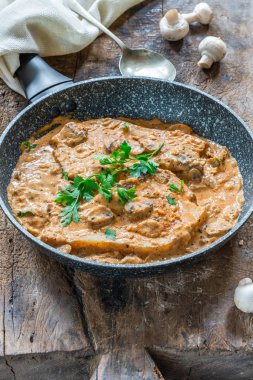 Bir tavada düğme mantar ve maydanoz ile kremsi cajun sos domuz pirzolası