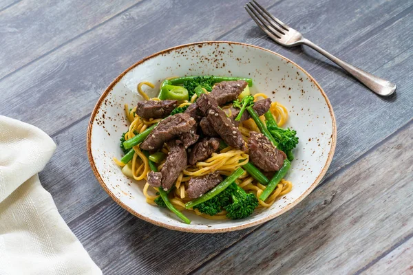 Honey and sesame beef noodles with green vegetables - high angle view