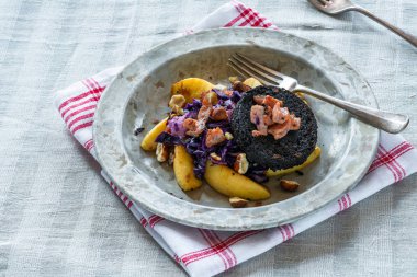 Kırmızı lahana, siyah puding ve gevrek pastırma ve ezilmiş fındık ile elma Sıcak salata.