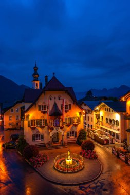 St. Gilgen, Avusturya - 11 Temmuz 2019: Salzkammergut bölgesinde popüler ve tanınmış bir seyahat noktası olan Sankt Gilgen köyünün şehir merkezinde Mozartplatz'da Rathaus (Belediye Binası). Gece görünümü