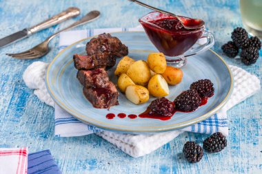 Böğürtlen soslu kızarmış geyik eti ve haşlanmış bebek patates.