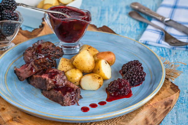 Pan-fried venison with blackberry sauce and boiled baby potatoes