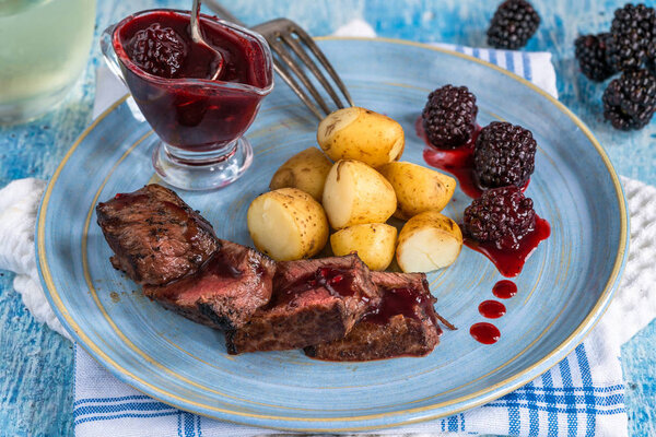 Pan-fried venison with blackberry sauce and boiled baby potatoes