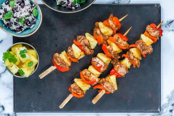 Jerk-style chicken and pineapple skewers with black bean rice - overhead view