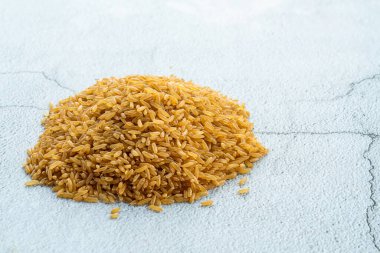 Açık arkaplanda bir yığın kuru kahverengi pirinç.