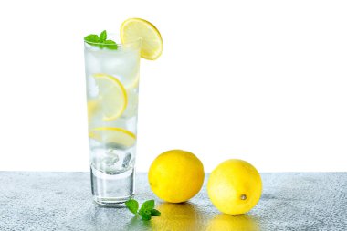 Limonlu ve buzlu su bir dilim limon ve hafif arkaplanda nane ile süslenir - ferahlatıcı soğuk alkolsüz içecek