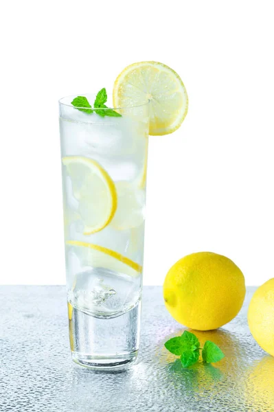 レモンとミントのスライスで装飾されたレモンと氷のキューブを背景に水 さわやかな冷たい非アルコール飲料 — ストック写真