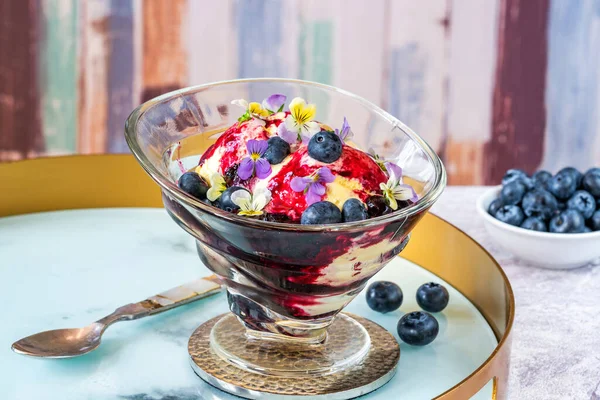 Glassdessert Med Blåbär Och Kardemumma Kompott Utsmyckad Med Ätbara Violblommor — Stockfoto