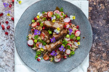 Çıtır ördek, hecelenmiş ve nar salatası, keman çiçekleri ile süslenmiş.