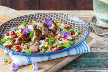 Çıtır ördek, hecelenmiş ve keman çiçekleriyle süslenmiş nar salatası.