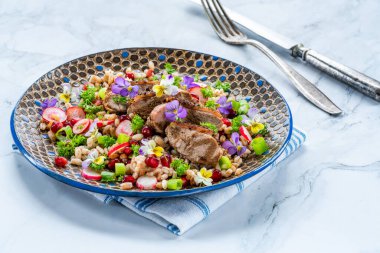 Çıtır ördek, hecelenmiş ve keman çiçekleriyle süslenmiş nar salatası.