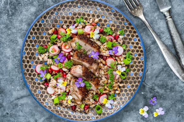 Çıtır ördek, hecelenmiş ve nar salatası, keman çiçekleri ile süslenmiş.