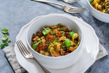 Tagliatelle makarna ve taze fesleğenli mercimek ve patlıcan yahnisi sağlıklı vejetaryen yemeği.