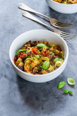 Tagliatelle makarna ve taze fesleğenli mercimek ve patlıcan yahnisi sağlıklı vejetaryen yemeği.