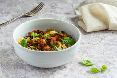 Tagliatelle makarna ve taze fesleğenli mercimek ve patlıcan yahnisi sağlıklı vejetaryen yemeği.