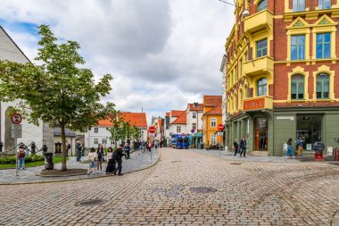 BERGEN, NORway - 15 AĞUSTOS 2025: Geleneksel renkli İskandinav binaları Norveç 'in Bergen kentindeki kaldırımlı bir cadde üzerindedir. Bergen Norveç 'in güneybatı kıyısında dağlar ve fiyortlarla çevrili bir şehirdir.