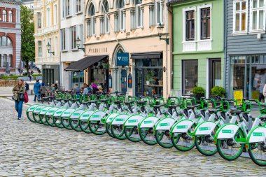 BERGEN, NORway - 15 AĞUSTOS 2025: Bir yeşil şehir kiralama e-bisiklet filosu Bergen 'de bir caddeye dizildi. Kiralık bisikletler şehirde alternatif ulaşım araçları sunuyor.