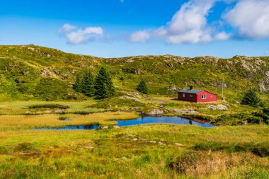 Bergen, Norveç yakınlarındaki Ulriken Dağı 'nda küçük bir gölü ve kırmızı ahşap kulübesi olan güzel bir manzara.