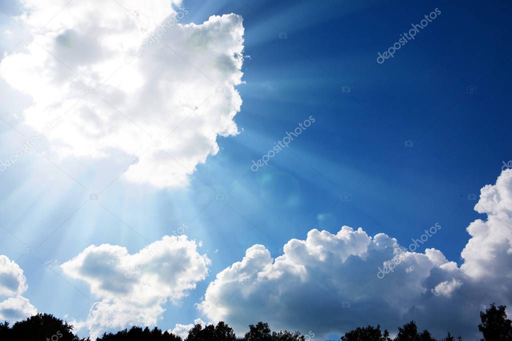 Blue sky with sunbeams and clouds. Sun rays.