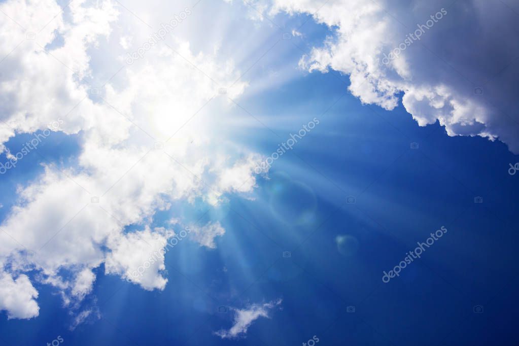 Blue sky with sunbeams and clouds. Sun rays.