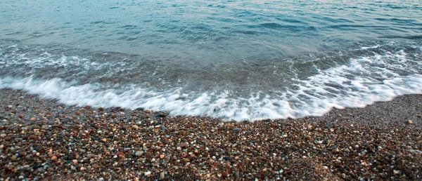 Vågor tvätta över grus stranden, makro skott. — Stockfoto
