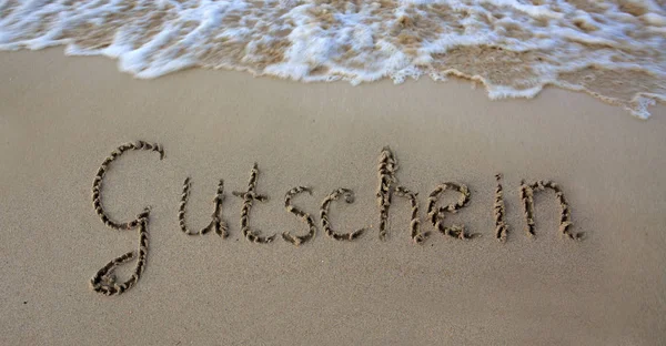 Слово купон написан на песке у моря . — стоковое фото