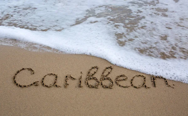 Word Caribbean geschreven op het zand in de buurt van de zee. — Stockfoto