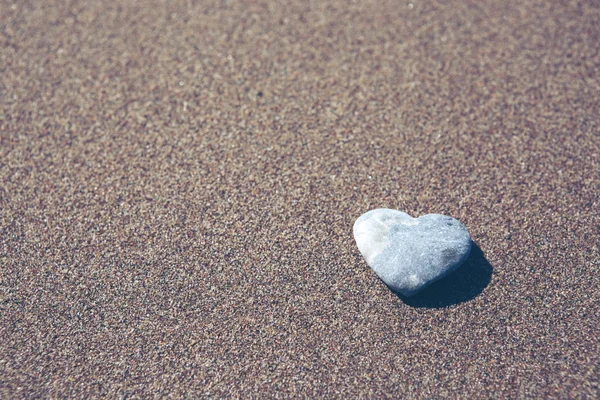 Grauer Stein in Herzform liegt auf Sand. — Stockfoto