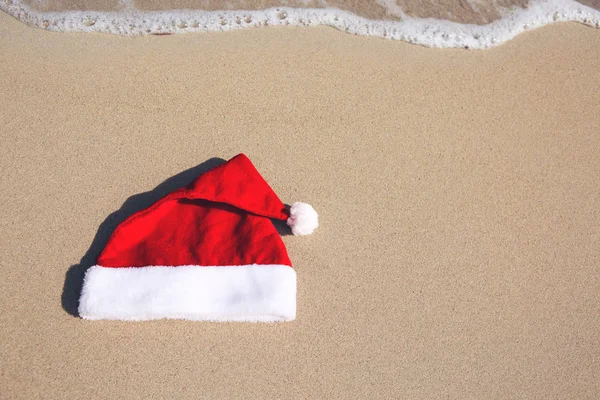 카리빈 해변에서 산타 클로스 모자를 쓰고 있습니다. 크리스마스 배경 — 스톡 사진