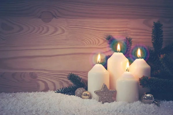 Four burning Advent candles and white snow.