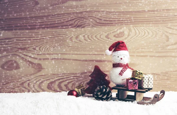 Снеговик с рождественскими подарками на санях изолирован на деревянном фоне . — стоковое фото