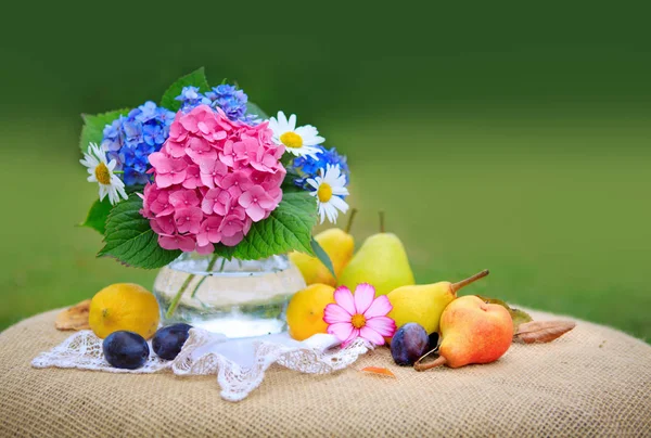 Buquê de flores coloridas em vaso de vidro e frutas frescas misturadas  . — Fotografia de Stock