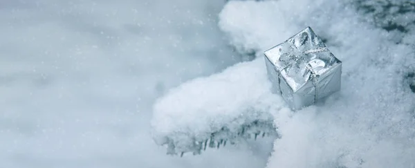 Zilveren kerstcadeau op witte sneeuw. Winter achtergrond. — Stockfoto