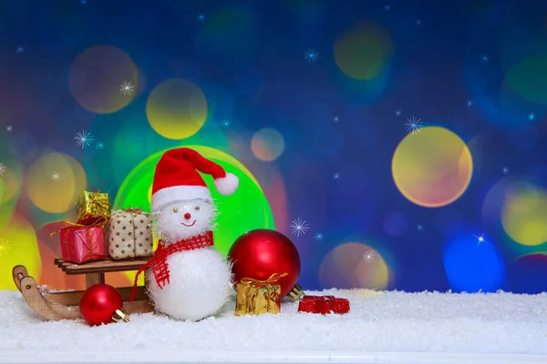 Schneemann mit Weihnachtsgeschenken und buntem Bokeh. Hintergrund zum neuen Jahr. — Stockfoto