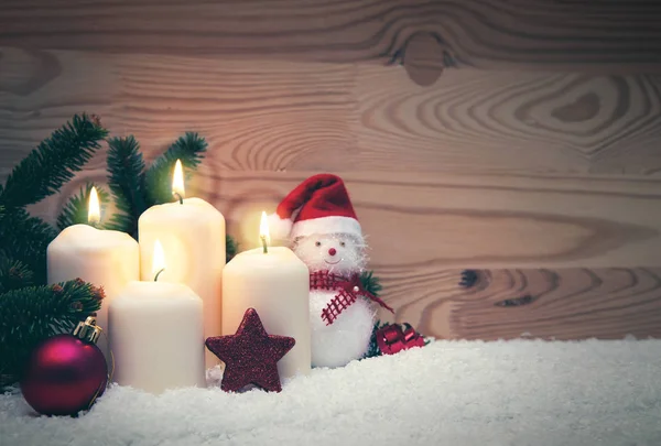 Čtyři hořící adventní svíčky a sněhulák s červeným vánoční ozdoby. — Stock fotografie