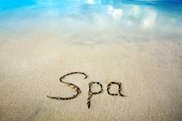Palabra Spa escrito en la arena cerca del mar.Concepto de vacaciones . — Foto de Stock