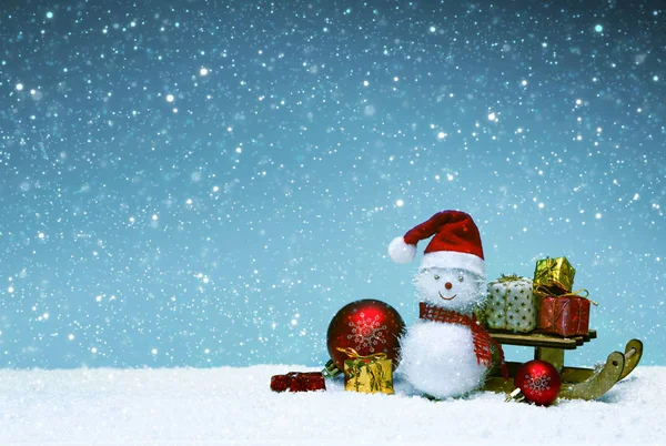 Рождественский снеговик с подарками на санях и снегопадом. — стоковое фото