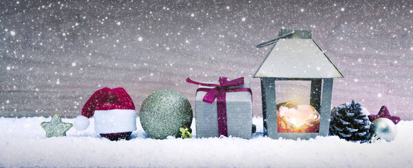 Christmas lantern on white snow and red Santa Hat .