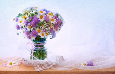 Chamomiles bouquett in vase on fabric background. clipart