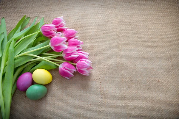 Uova di Pasqua e tulipani. Decorazione festiva su sfondo stoffa . — Foto Stock